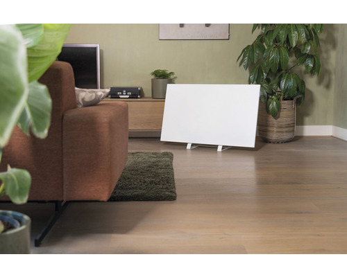 Woonkamer met bank, kamerplanten, dressoir en een wit infrarood verwarmingspaneel.