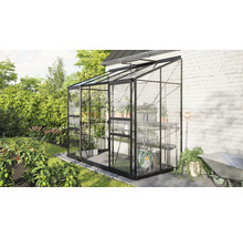 Glazen kas met planken en tuingereedschap in de tuin