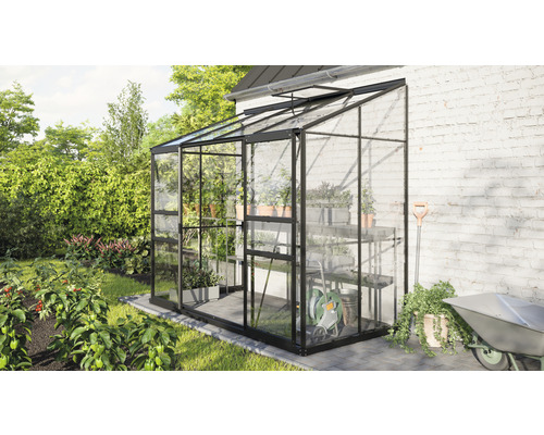 Glazen kas met planken en tuingereedschap in de tuin