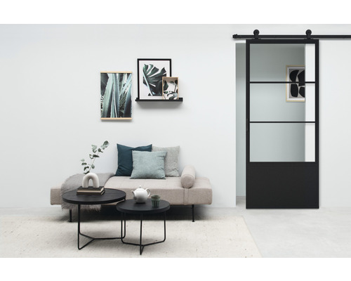 Woonkamer met bank, ronde tafels, wanddecoraties en glazen schuifdeur