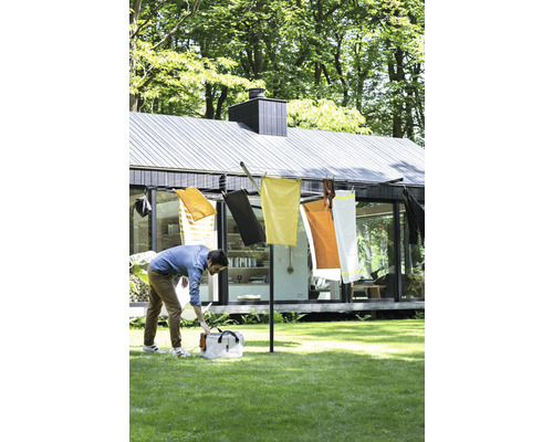 Droogmolen in de tuin met opgehangen textiel en man die een tas opent