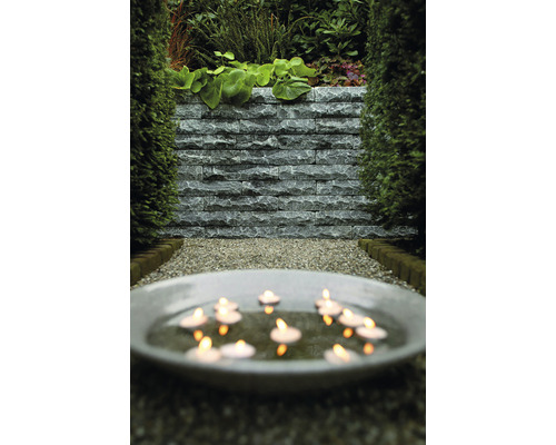 Tuin met stenen muur, grindpad en waterschaal met kaarsen