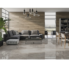 Woonkamer met grijze vloertegels, houten wand, grijze bank en eettafel met stoelen