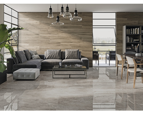 Woonkamer met grijze vloertegels, houten wand, grijze bank en eettafel met stoelen