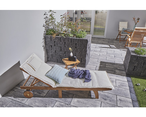 Buitenkant met houten ligstoel, plantenbakken en stenen vloer