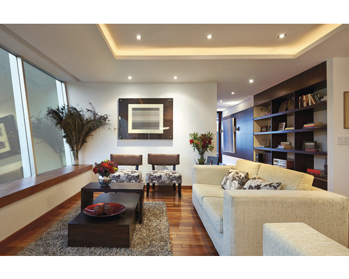 Woonkamer met bank, fauteuils, salontafels en planken