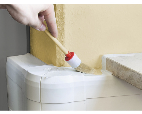 Hand schildert met een ronde kwast verf op een muur.