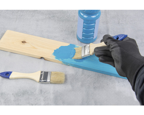 Iemand schildert een houten plank met een kwast en verf.