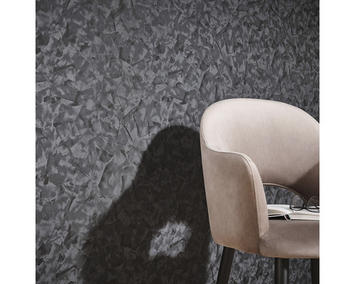 Close-up van een wandbehang met abstracte textuur en een deel van een stoel