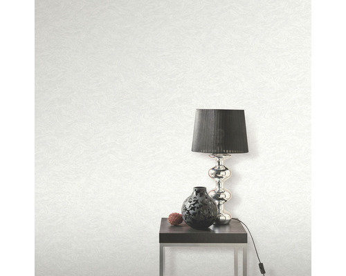 Licht behang met textuur, tafellamp, decoratie en bijzettafel in de kamer.