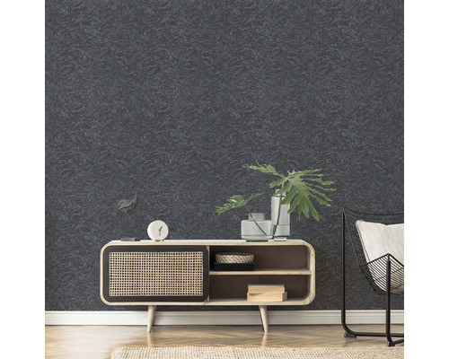 Close-up van een gestructureerd, donker behang in de woonkamer, gecombineerd met een houten kast en een metalen stoel.
