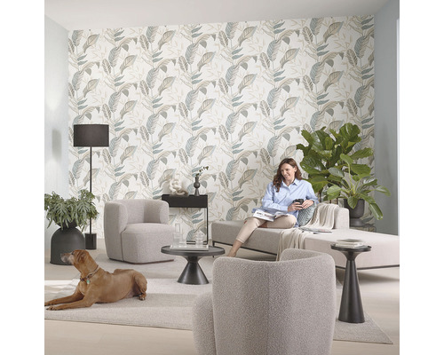 Woonkamer met bladerbehang, bank, fauteuil, staande lamp en hond