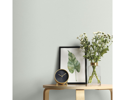 Woonkamer scène met tafel, klok, bloemen en ingelijste foto aan een muur