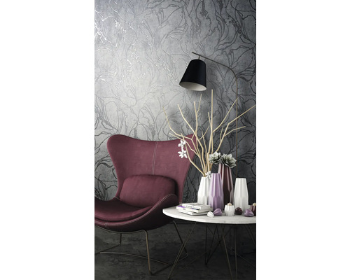 Woonkamer met fauteuil, tafel en behang met bloemmotief