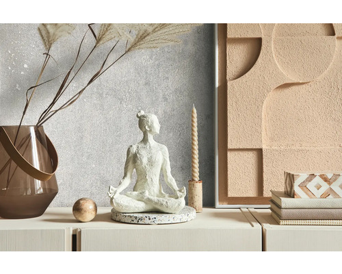 Decoratieve scène met een meditatiefiguur, een vaas, een kaars en een wanddecoratie op een dressoir.