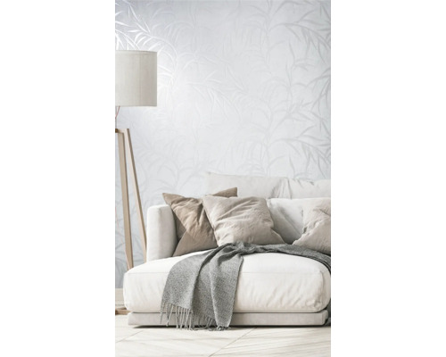 Woonkamer met bank, kussens, deken, vloerlamp en behang met plantenpatroon
