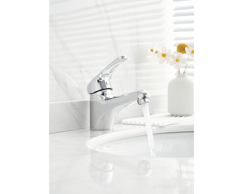 Glanzende metalen kraan op een witte wastafel