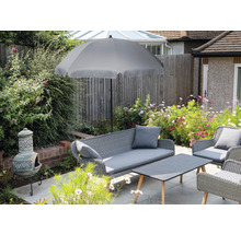 Tuinscene met grijze parasol, rotan zitgroep en leemkachel op een terras