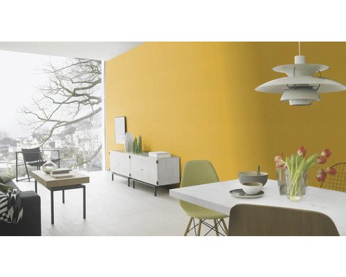 Lichte woonkamer met gele muur, dressoir en eettafel.