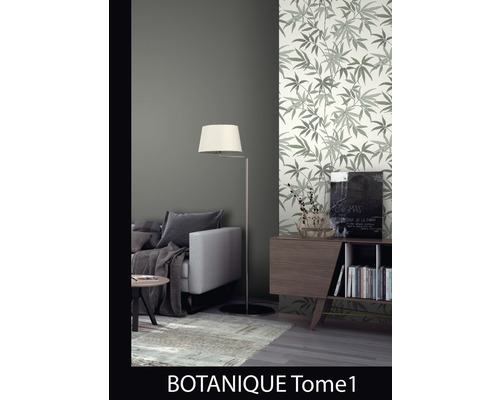 Woonkamer met bank, vloerlamp en een muur met behang met bladerpatroon.