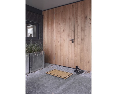 Entree met deurmat voor een houten deur