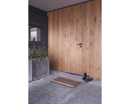 Entree met houten deur, deurmat en plantenbakken