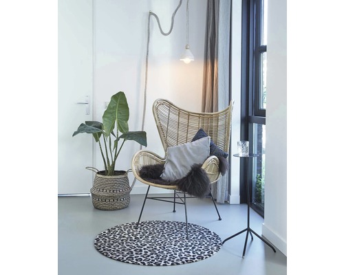 Lichte kamer scène met rotan stoel, decoratief tapijt, potplant en bijzettafel