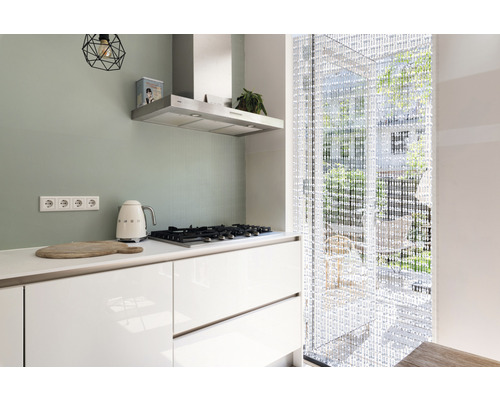 Moderne keuken met kookplaat, afzuigkap, kralengordijn en keukengerei.