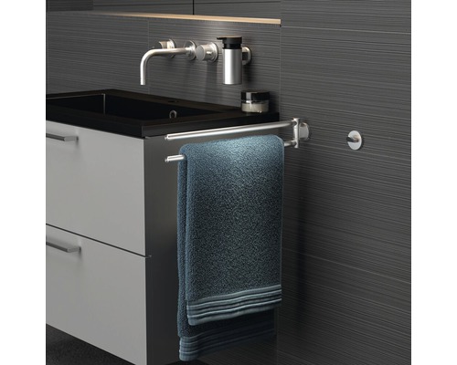 Badkamer met wastafel, kraan, handdoekrek en handdoek.