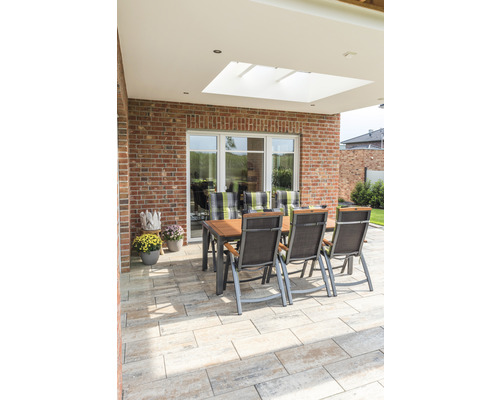 Tuinzitgroep op betegeld terras met bakstenen muur