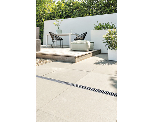 Terrasscène met afwateringsgoot, tafel, stoelen, planten en een poef