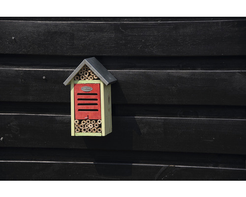 Insectenhotel met bamboebuizen en dak aan een houten wand