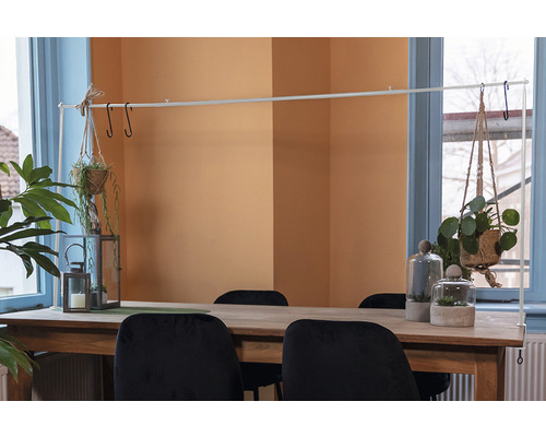 Eettafel met decoraties, waaronder hangplanten, windlichten en planten onder glazen stolpen.