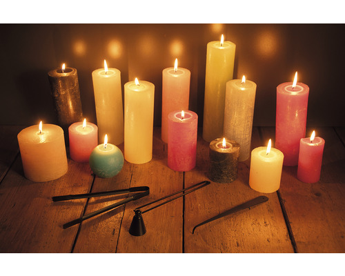 Kaarsen in verschillende maten en kleuren met kaarsendover en lontknipper op een houten tafel