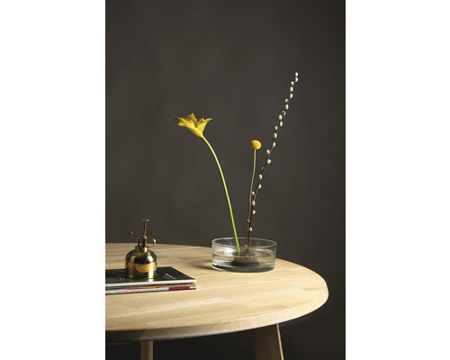 Bloemen in een glazen vaas op een houten tafel met bloemenspuit.