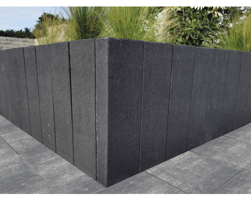 Hoge plantenbak van betonblokken beplant met planten