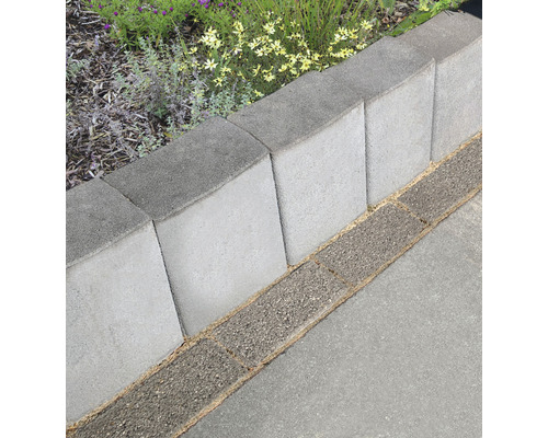Rij grijze gazonrandstenen van beton naast een verhard pad