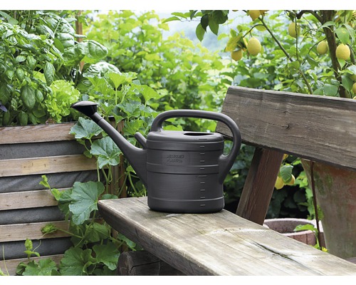 Kunststof gieter op een houten bank in de tuin