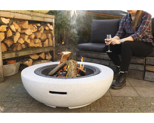 Vuurplaats van steen met houtvuur en zittend persoon