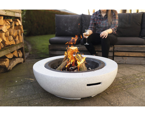 Vuurplaats met brandhout en zittende persoon in de tuin