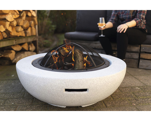 Vuurplaats met vonkenvanger in de tuin met hout en zittend persoon