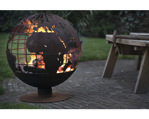 Vuurkorf in de vorm van een wereldbol met uitgesneden wereldkaart en brandend hout in de tuin