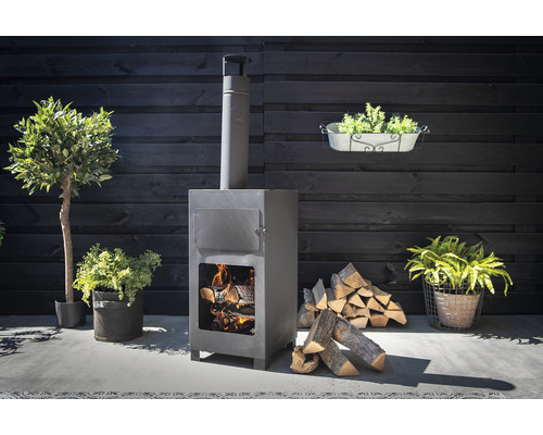 Tuinscene met een grijze buitenkachel met hout en planten
