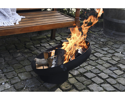 Vuurkorf met hout en vlammen buiten naast een houten bank.