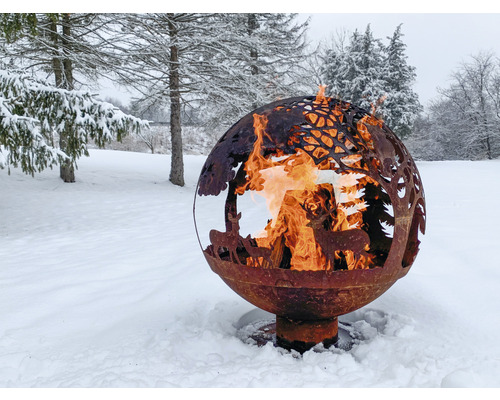 Vuurplaats in bolvorm met dieren- en boommotieven in een besneeuwde tuin