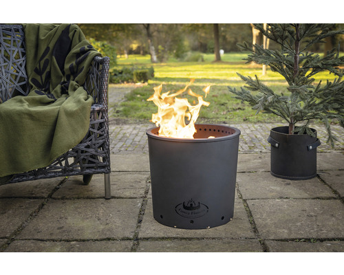 Metalen vuurkorf in de tuin met stoel en plant