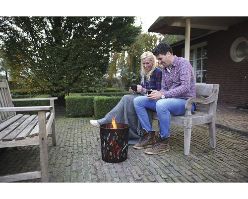 Een paar zit op een bank in de tuin naast een vuurkorf op een heldere dag