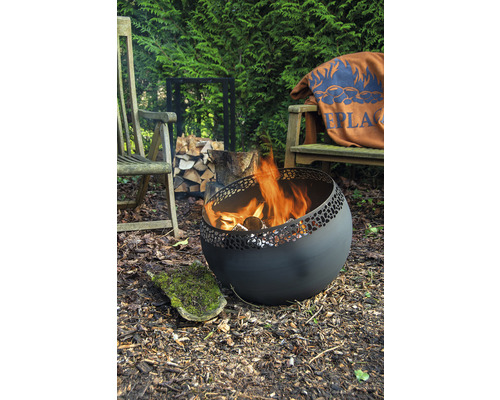 Vuurplaats met hout in de tuin, omgeven door houten stoelen en een stapel hout