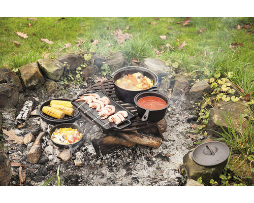 Buitenkeuken met Dutch Oven, grillpan en diverse gerechten boven open vuur.