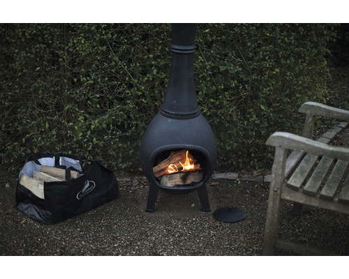 Tuinscene met chimenea vuurplaats, brandhout en tuinbank